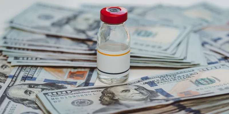 insulin vial next to stacks of 100 dollar bills