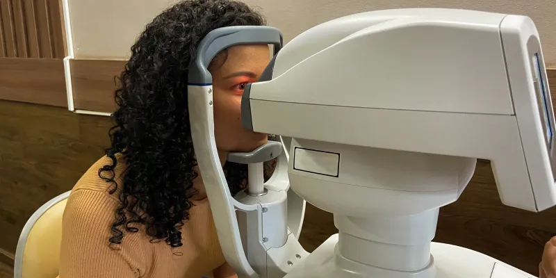 A Black woman gets her eyes examined by a machine