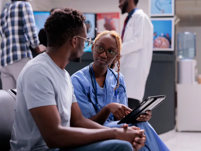 African American female nurse speaking with African American male patient