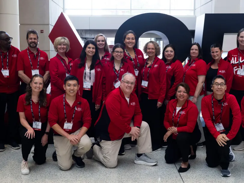 ADA staff volunteer red shirts stands before large ADA branding at Scientific Sessions..
