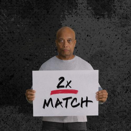 African American man holding sign that says 2x Match
