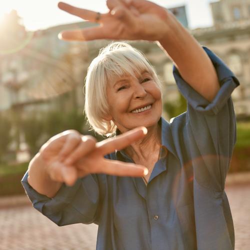 Smiling carefree senior woman giving peace signs