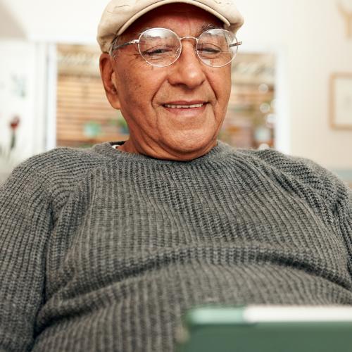 Smiling senior man with glasses looking at laptop computer