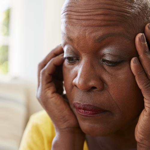 Senior African American woman looking concerned with her hands on her face