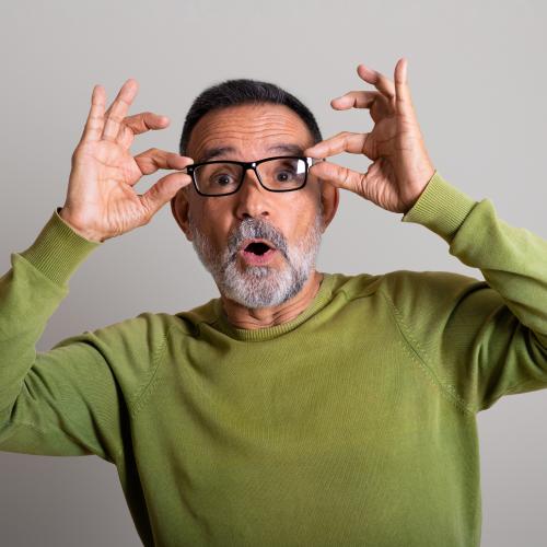 Surprised middle-age man grabbing at the sides of his glasses