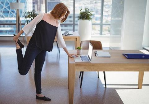 Woman doing balance exercises in front of laptop computer