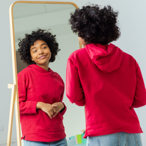 A younger woman looks in the mirror and smiles at herself. 