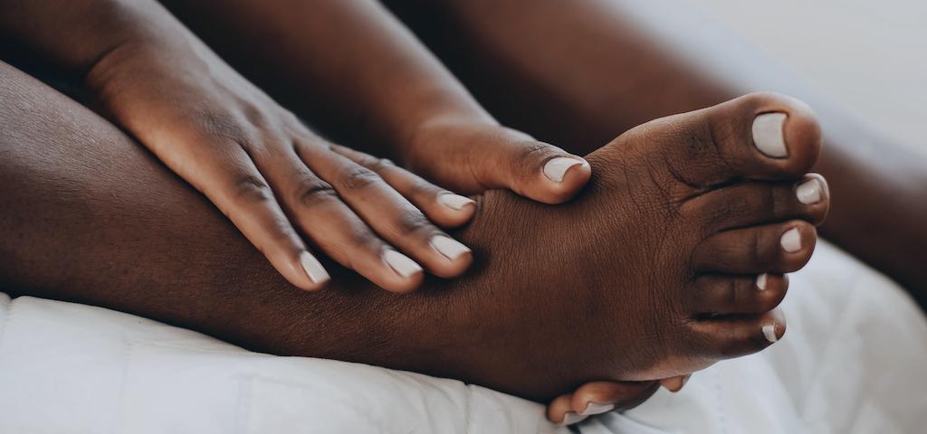 African American woman rubbing bare feet