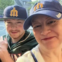 Photograph: Smiling woman and young man wearing Seattle Mariners baseball caps.