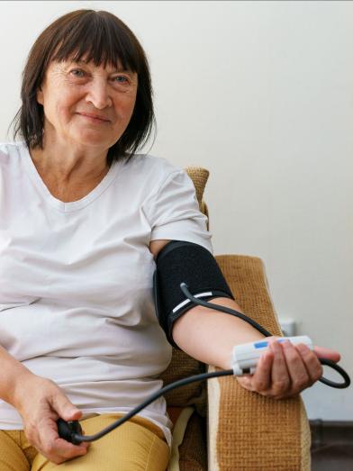 Senior woman checking blood pressure on couch