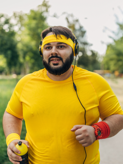 A stocky man wearing yellow exercise clothes is outside walking