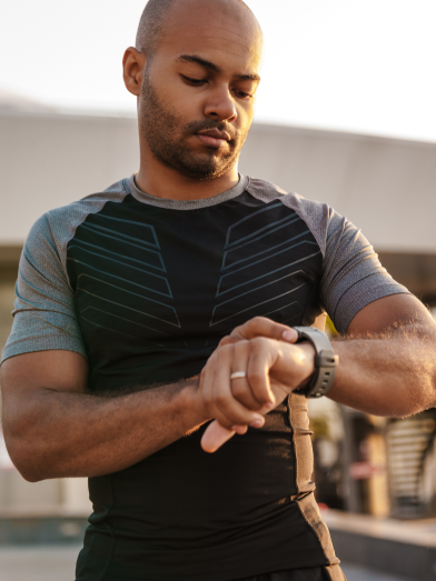 A man looks at his exercise watch while outside.