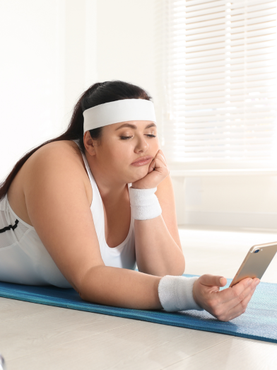 A young woman wearing gym clothes is boredly looking at her phone