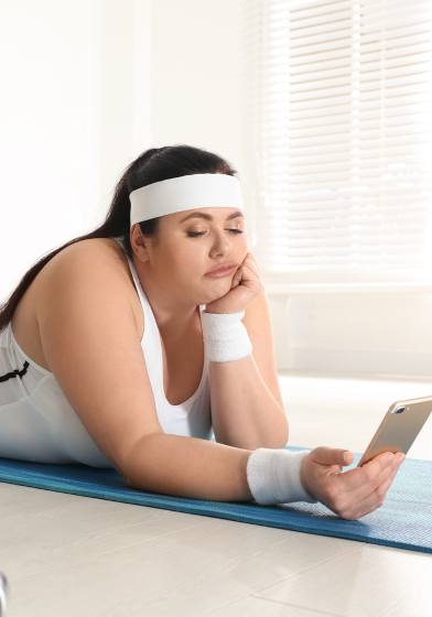A young woman wearing gym clothes is boredly looking at her phone