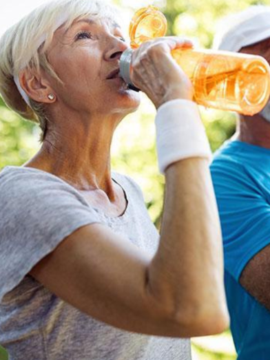 Senior woman drinking an orange sports drink.