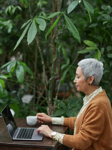 Senior woman taking diabetes risk test on laptop ad desk in garden