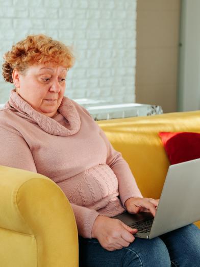 Senior obese woman with surprised look on face looking at laptop computer