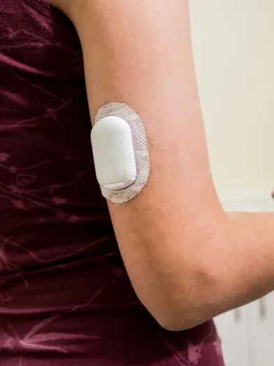 A woman with a insulin pump on her arm holds a smartphone.