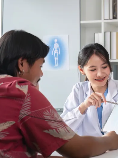 Female doctor explains a document to a smiling male patient in an office.