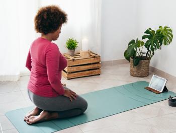 African American woman kneeling on yoga mat