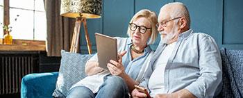Senior couple on couch looking at tablet computer