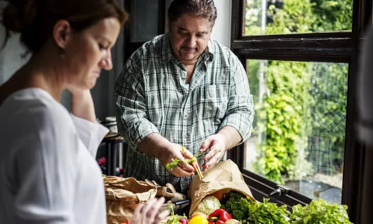 Husband and wife preparing vegetables in kitchen