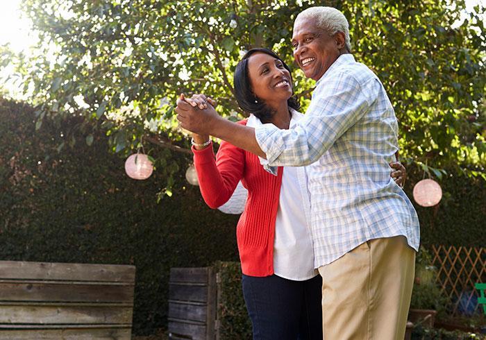 Senior black couple dancing in their back garden