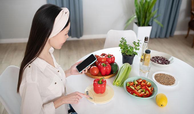 young-woman-with-smartphone-weighing-red-pepper-eyeball-carbs